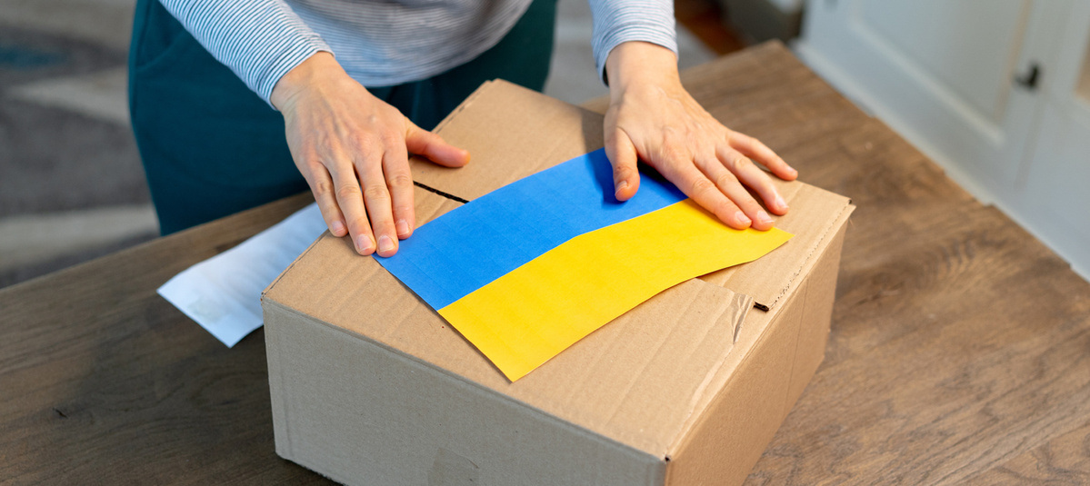 1387052661 An unrecognisable person is closing a donation box . Help for people in need in Ukraine
